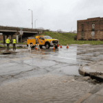 Wet street and drainage overflow representing delayed visibility of public system failures